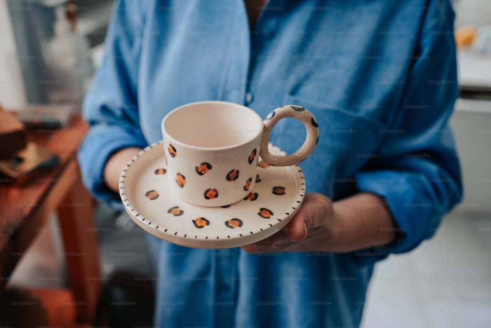 una persona sosteniendo una taza de café y un platillo