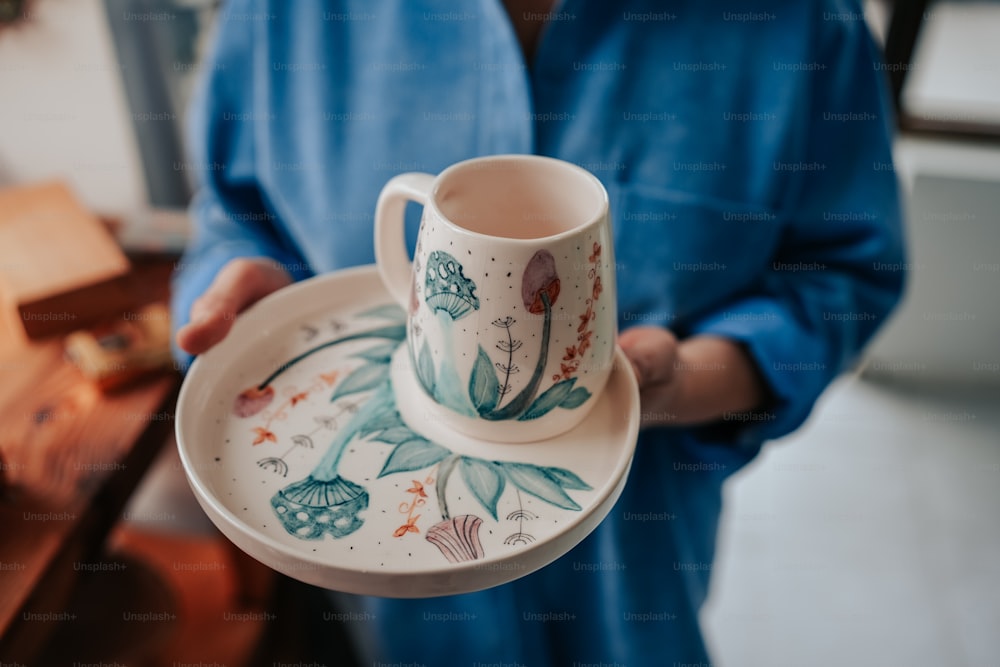 a person holding a plate with a cup on it