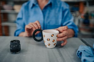 uma pessoa sentada em uma mesa segurando uma xícara de café