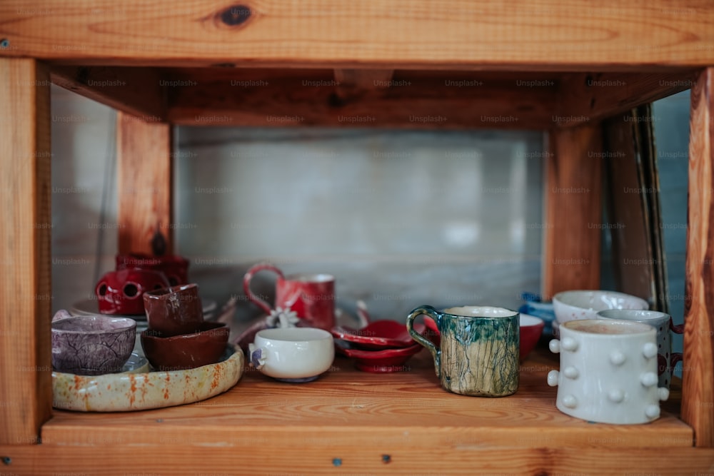 a shelf filled with cups and bowls on top of a wooden shelf
