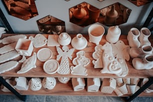 a wooden table topped with lots of white pottery