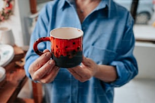 a person holding a red and black coffee mug