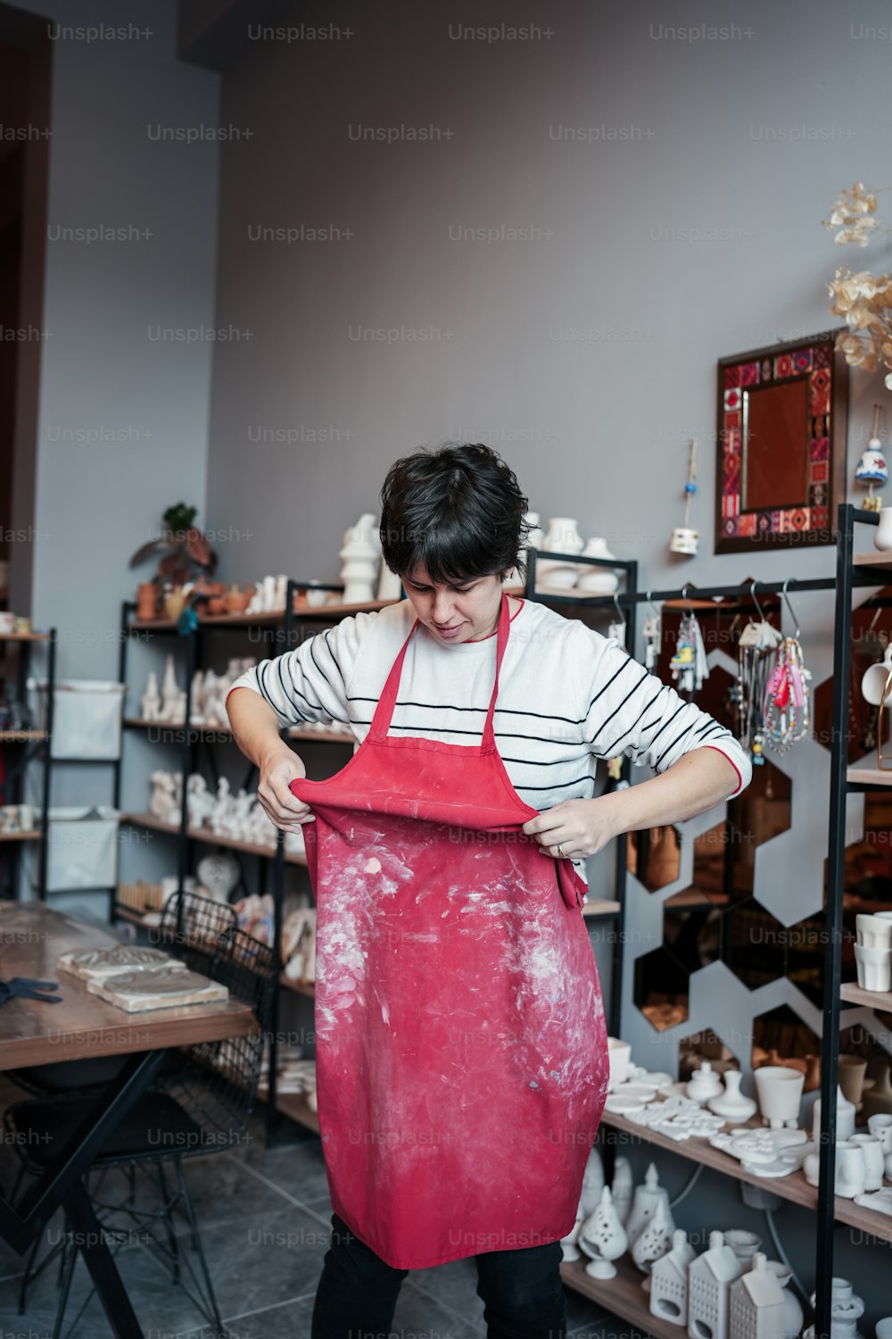 uma mulher em um avental vermelho trabalhando em uma peça de cerâmica