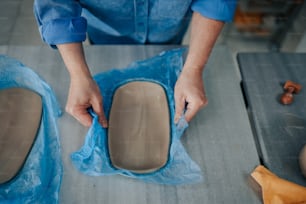 uma pessoa em uma camisa azul está fazendo um pedaço de cerâmica