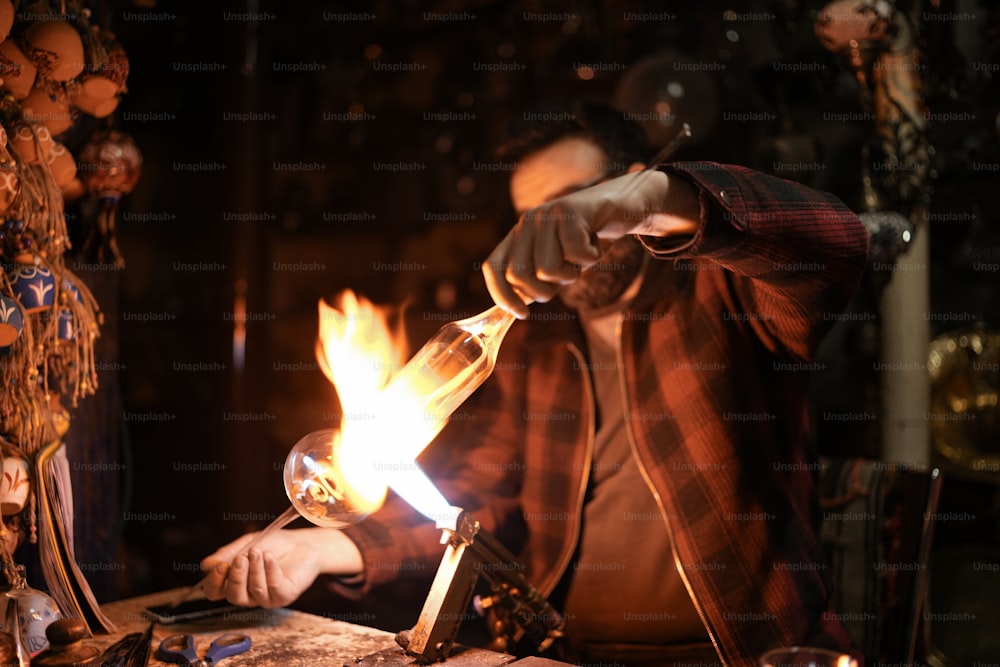 a man lighting a candle on top of a wooden table