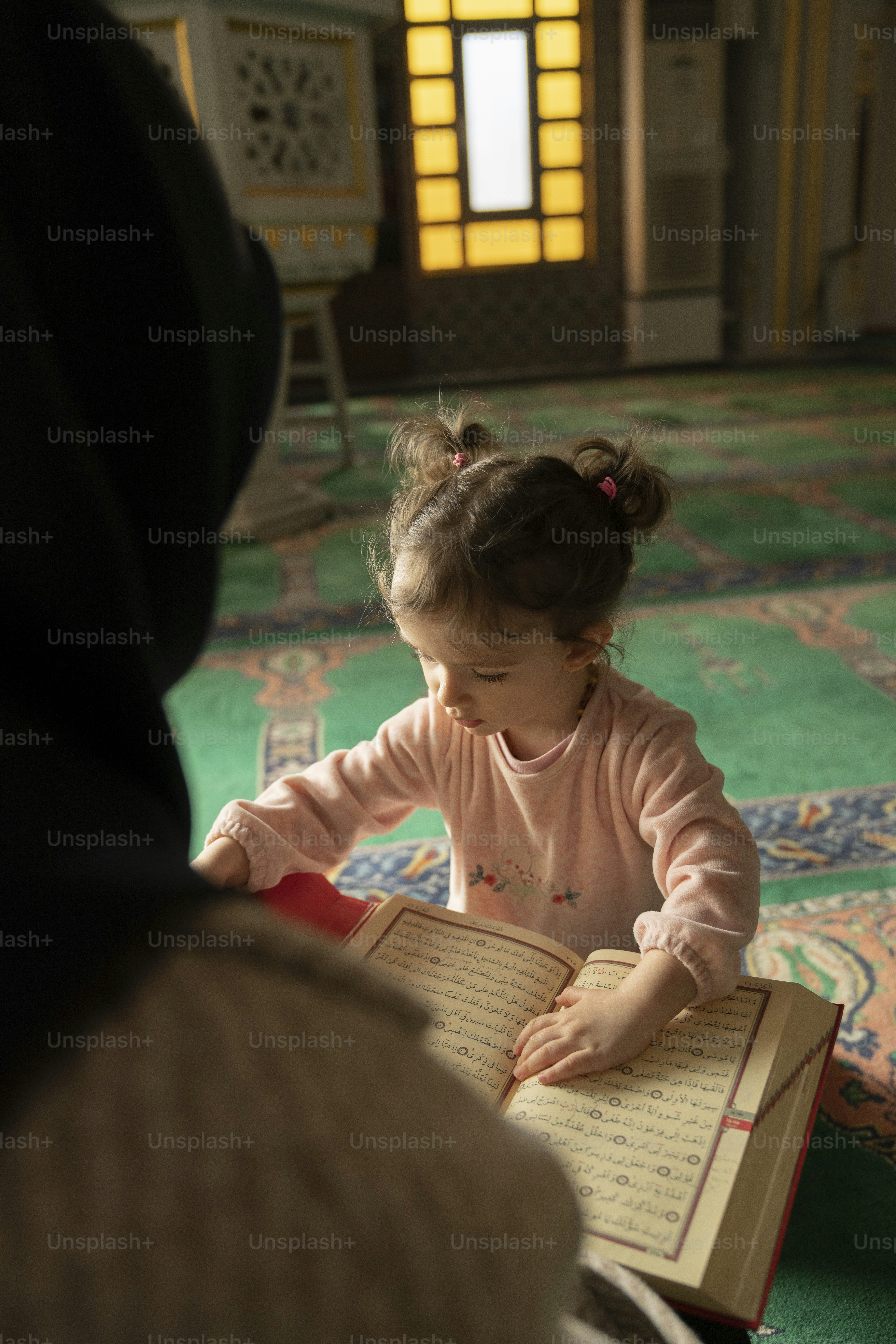 a little girl sitting on the floor reading a book