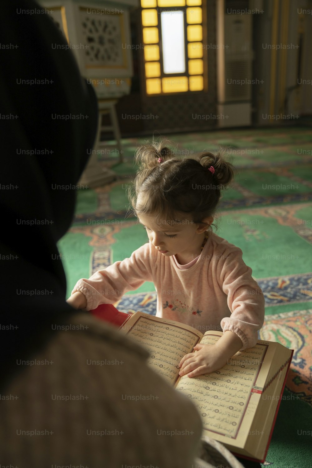 a little girl sitting on the floor reading a book