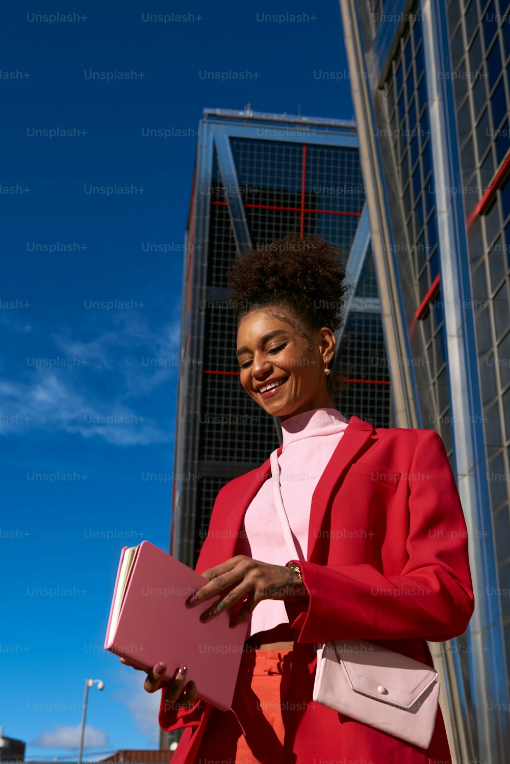 a woman in a red suit holding a pink folder