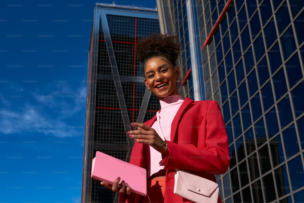 a woman in a red suit holding a pink folder