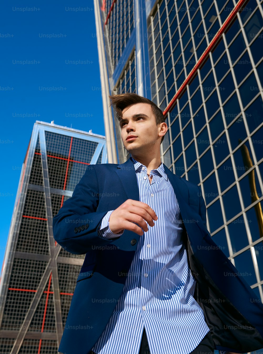 Un homme en costume se tient devant un immeuble