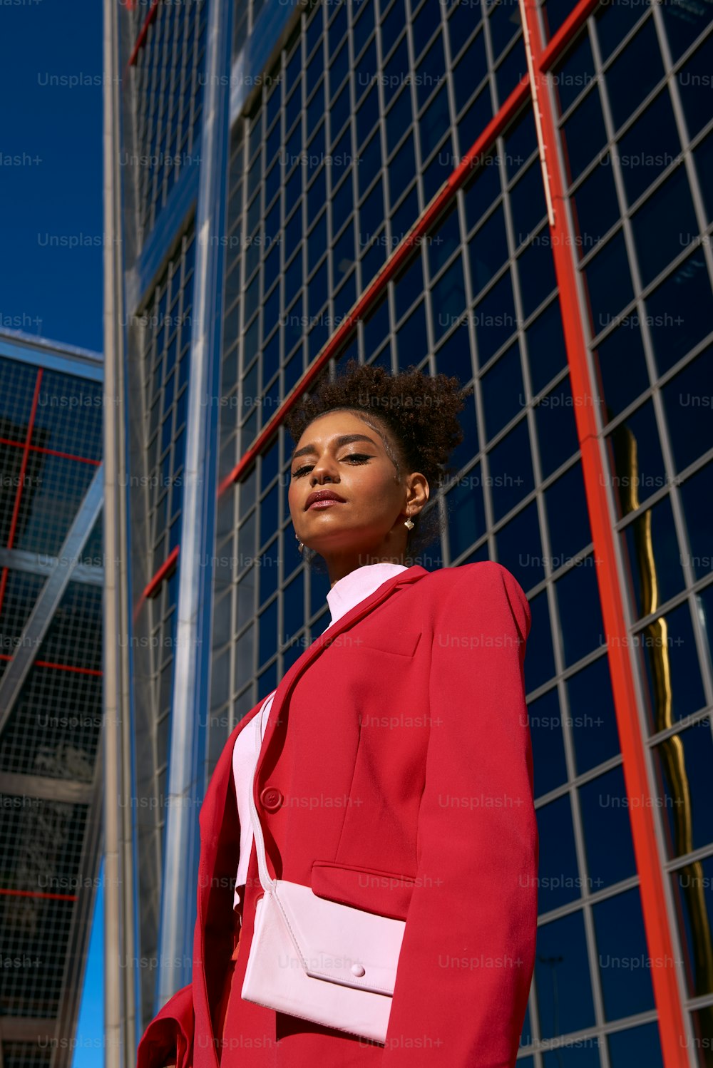 a woman in a red suit standing in front of a building