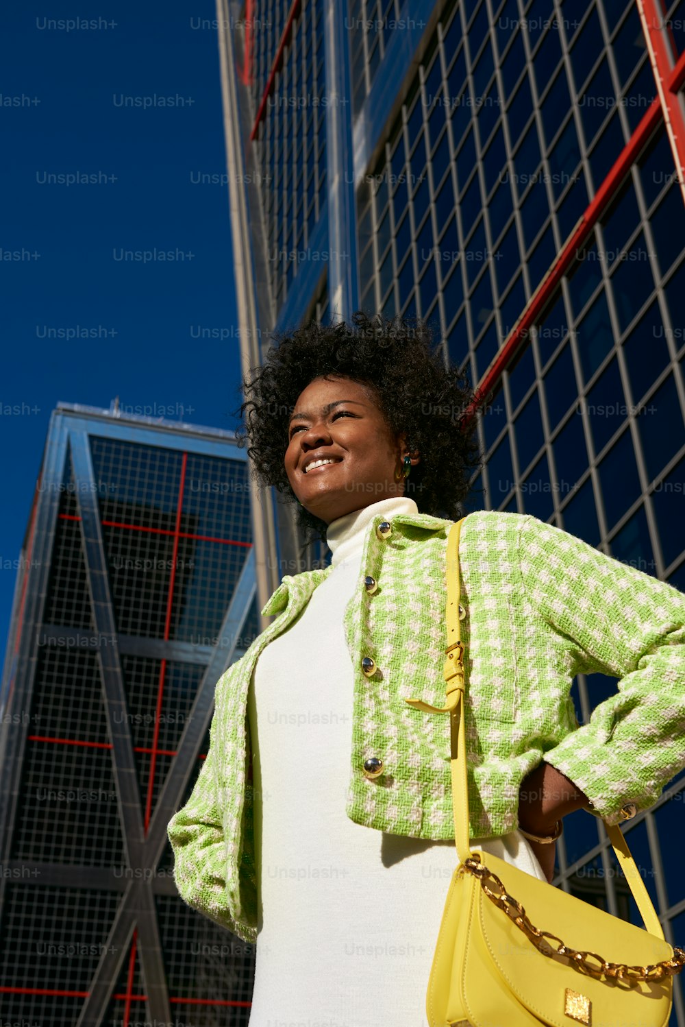 uma mulher em pé na frente de um edifício segurando uma bolsa amarela