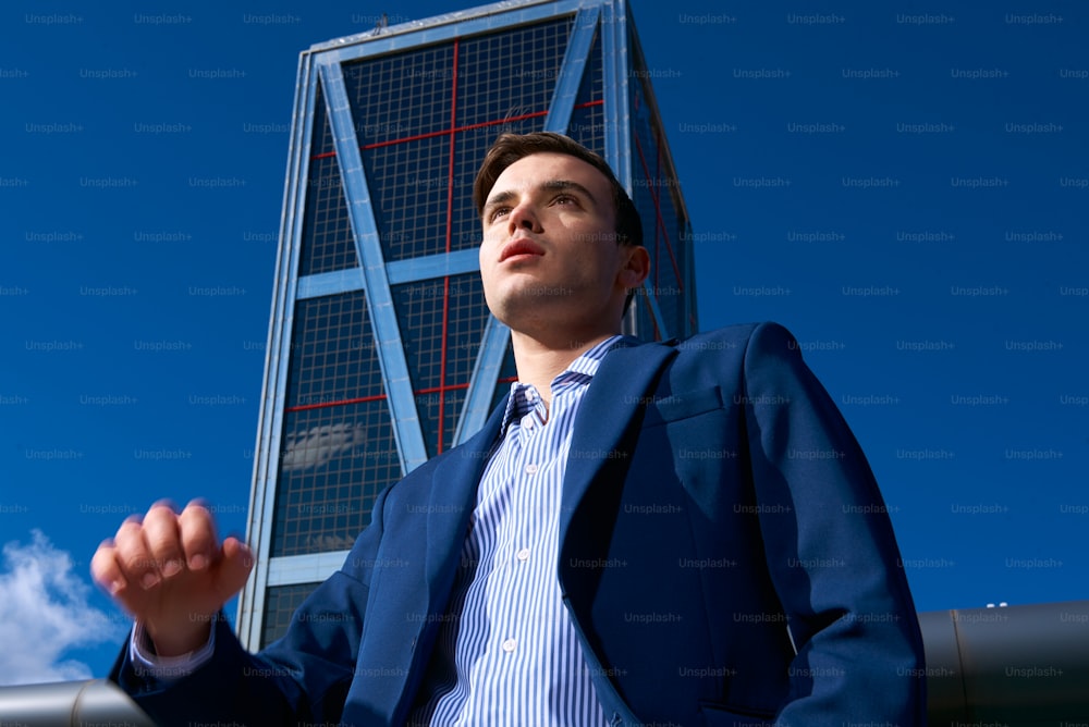 a man in a suit standing in front of a tall building
