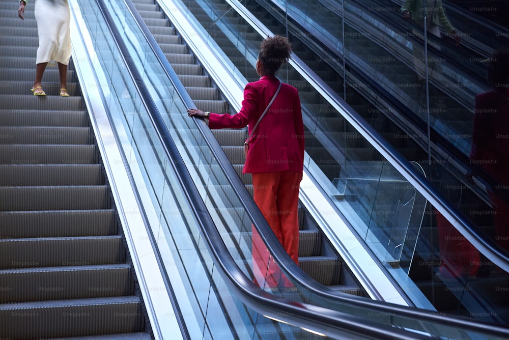 Una mujer subiendo una escalera mecánica por un conjunto de escaleras