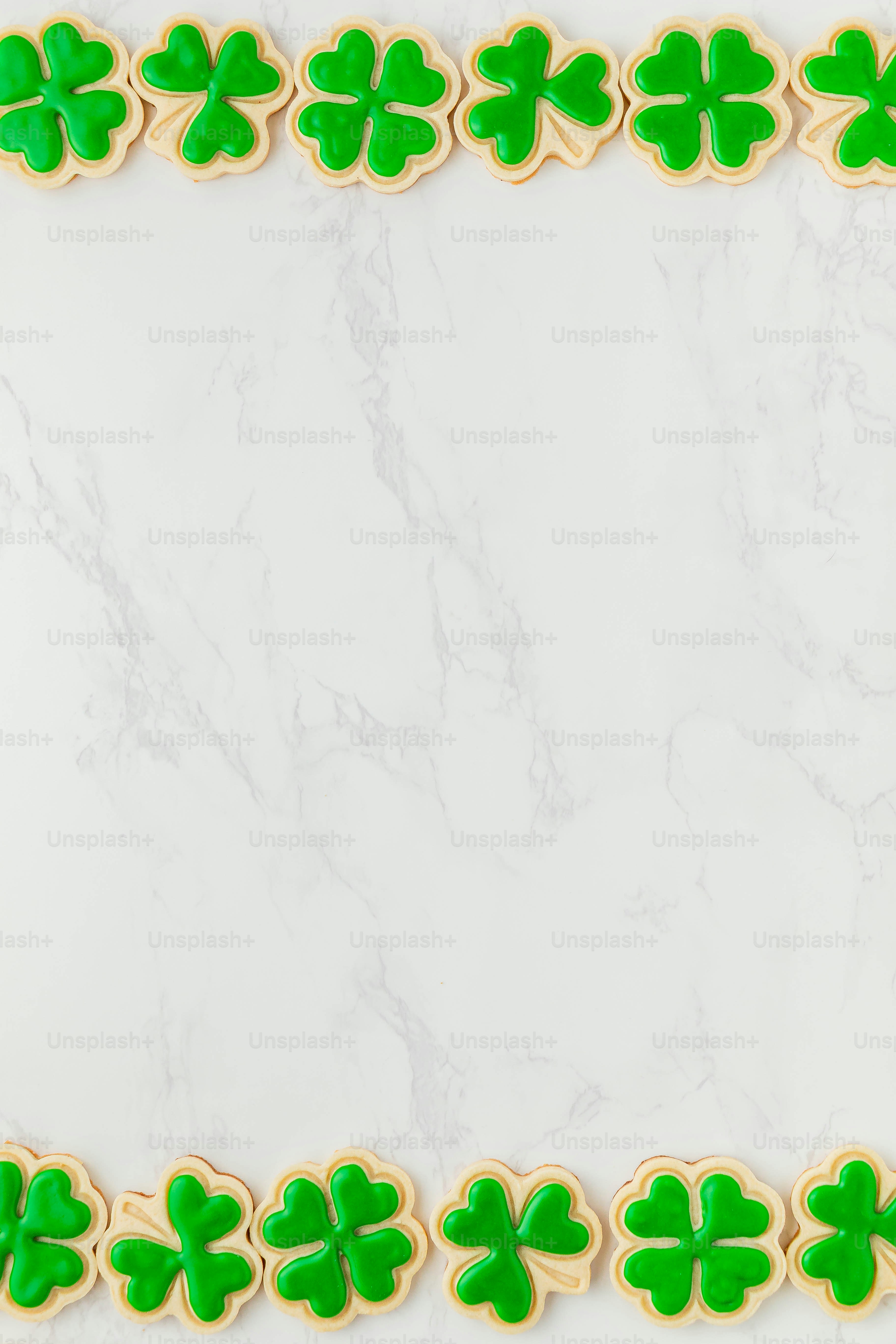 a white marble table topped with green shamrock cookies