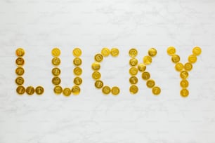 a word made out of gold coins sitting on top of a white table
