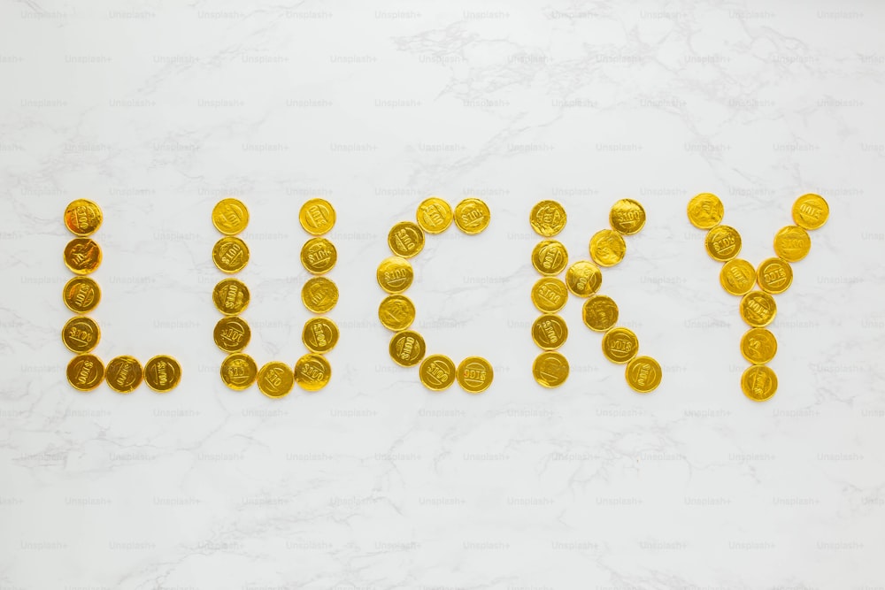 a word made out of gold coins sitting on top of a white table