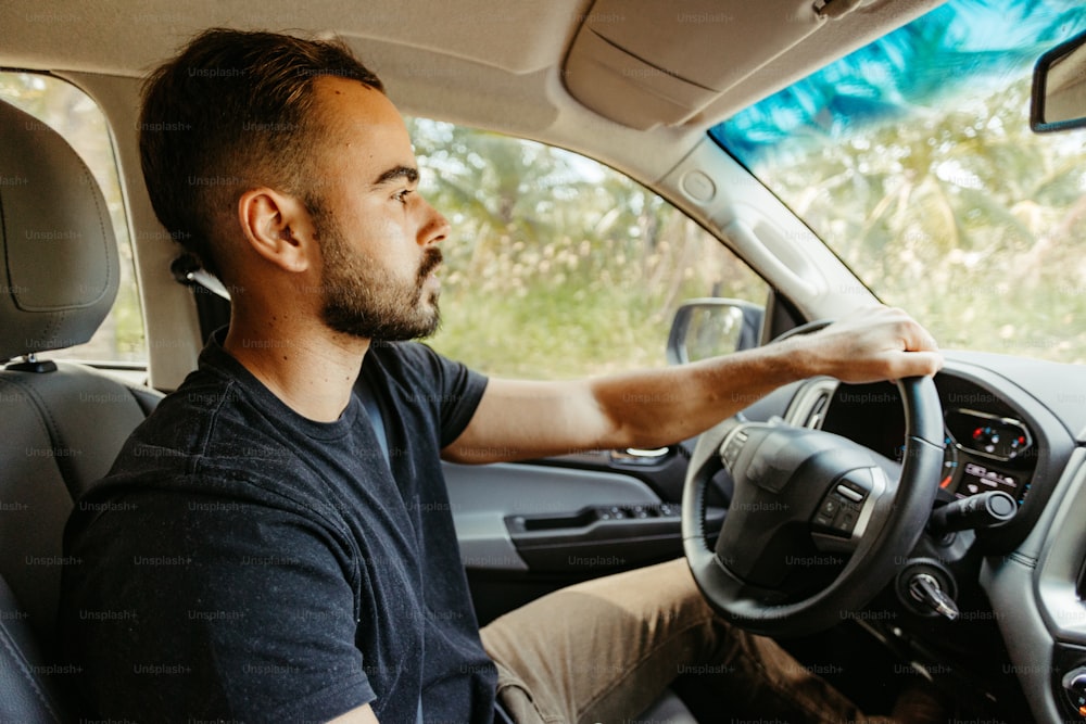 a man driving a car with a steering wheel