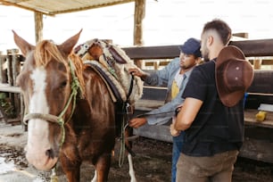 a couple of men standing next to a brown horse