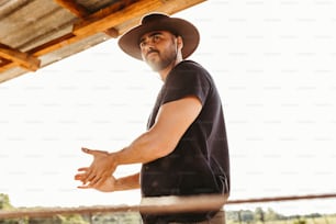 a man wearing a cowboy hat standing in front of a fence