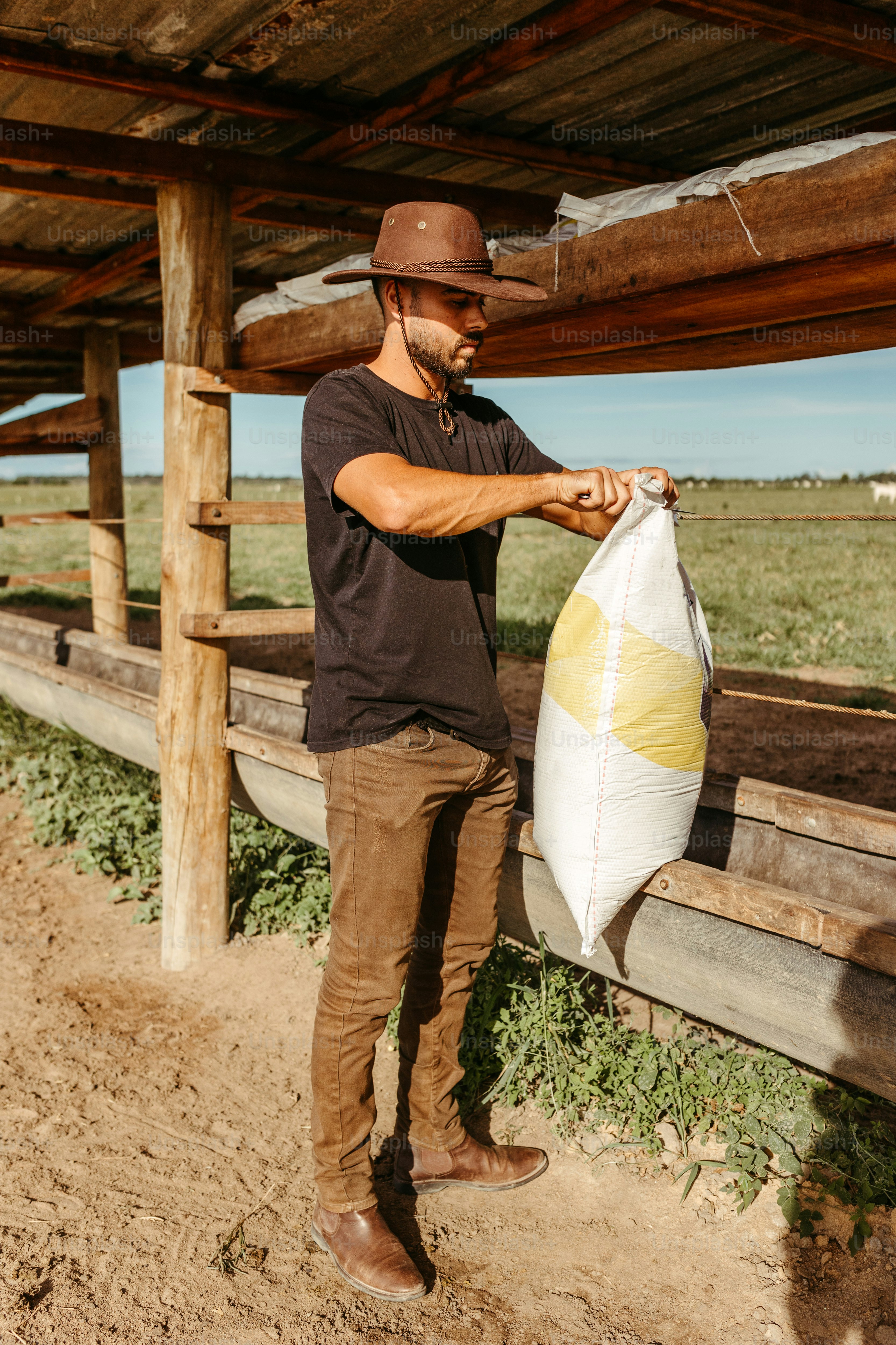 a man standing next to a wooden fence holding a bag