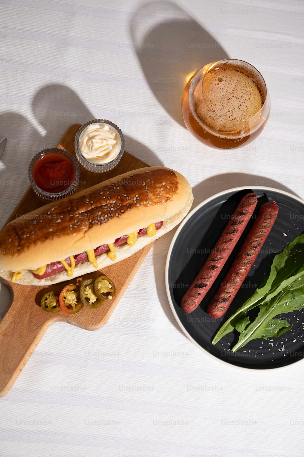 a hot dog on a bun next to a plate of hot dogs