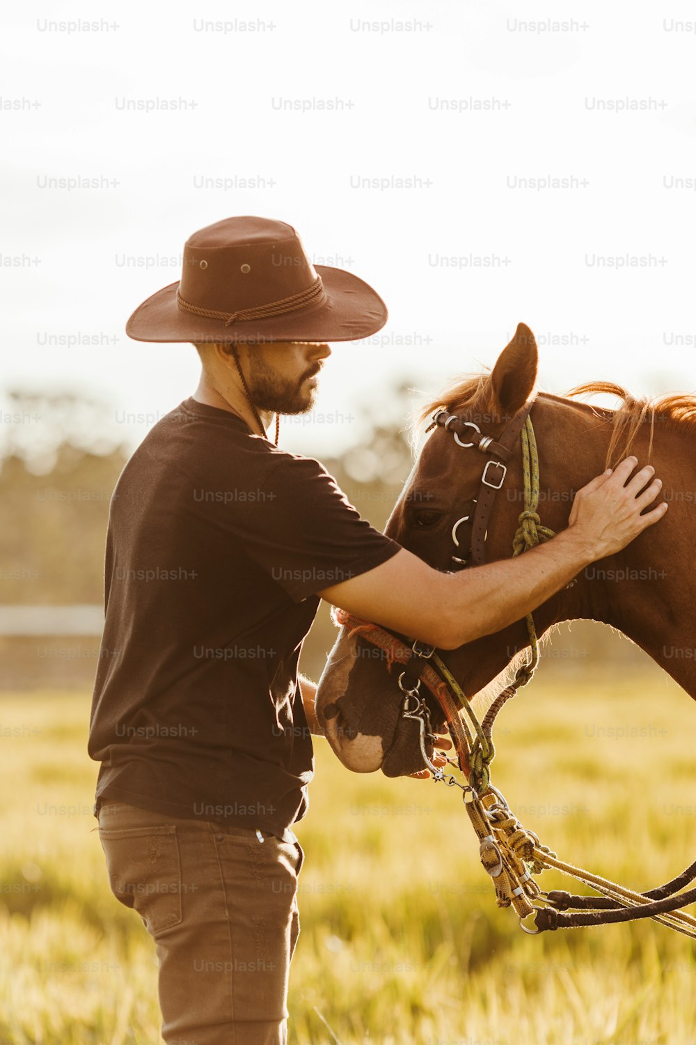 a man in a cowboy hat petting a horse