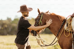 a man in a cowboy hat petting a horse