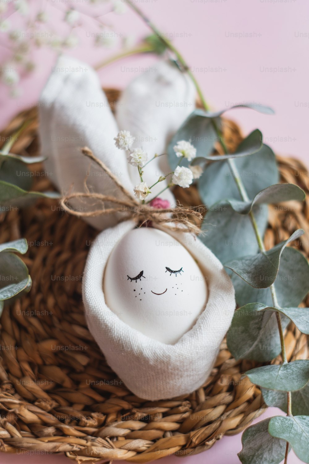a white egg sitting on top of a basket next to a plant