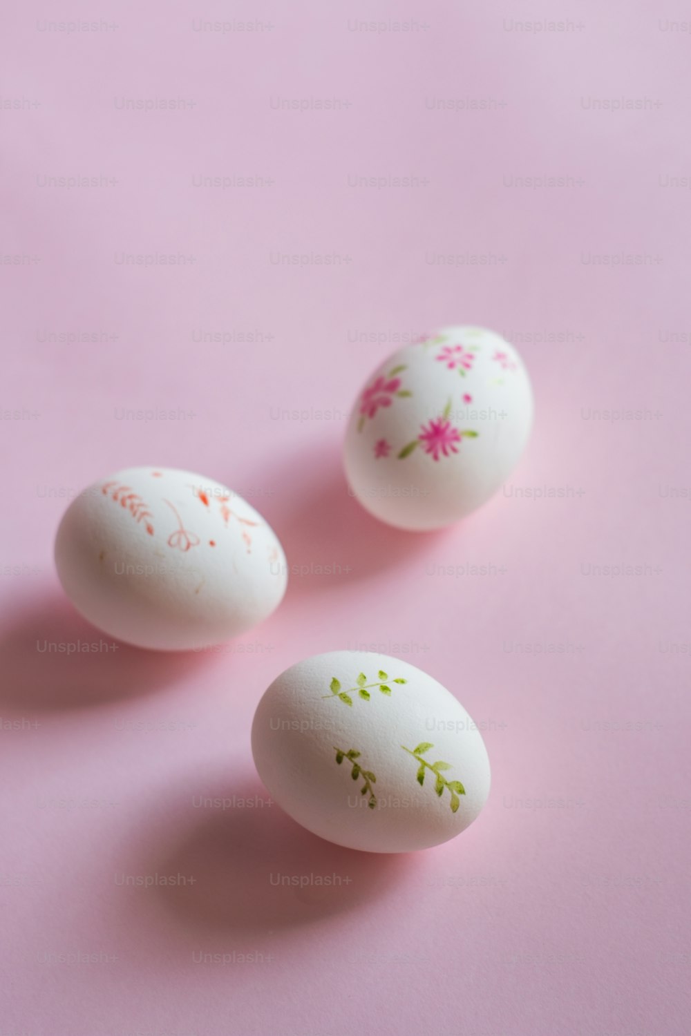 three decorated eggs sitting on top of a pink surface
