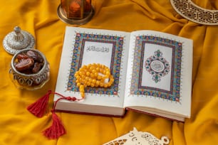an open book with beads and a tassel on a yellow cloth