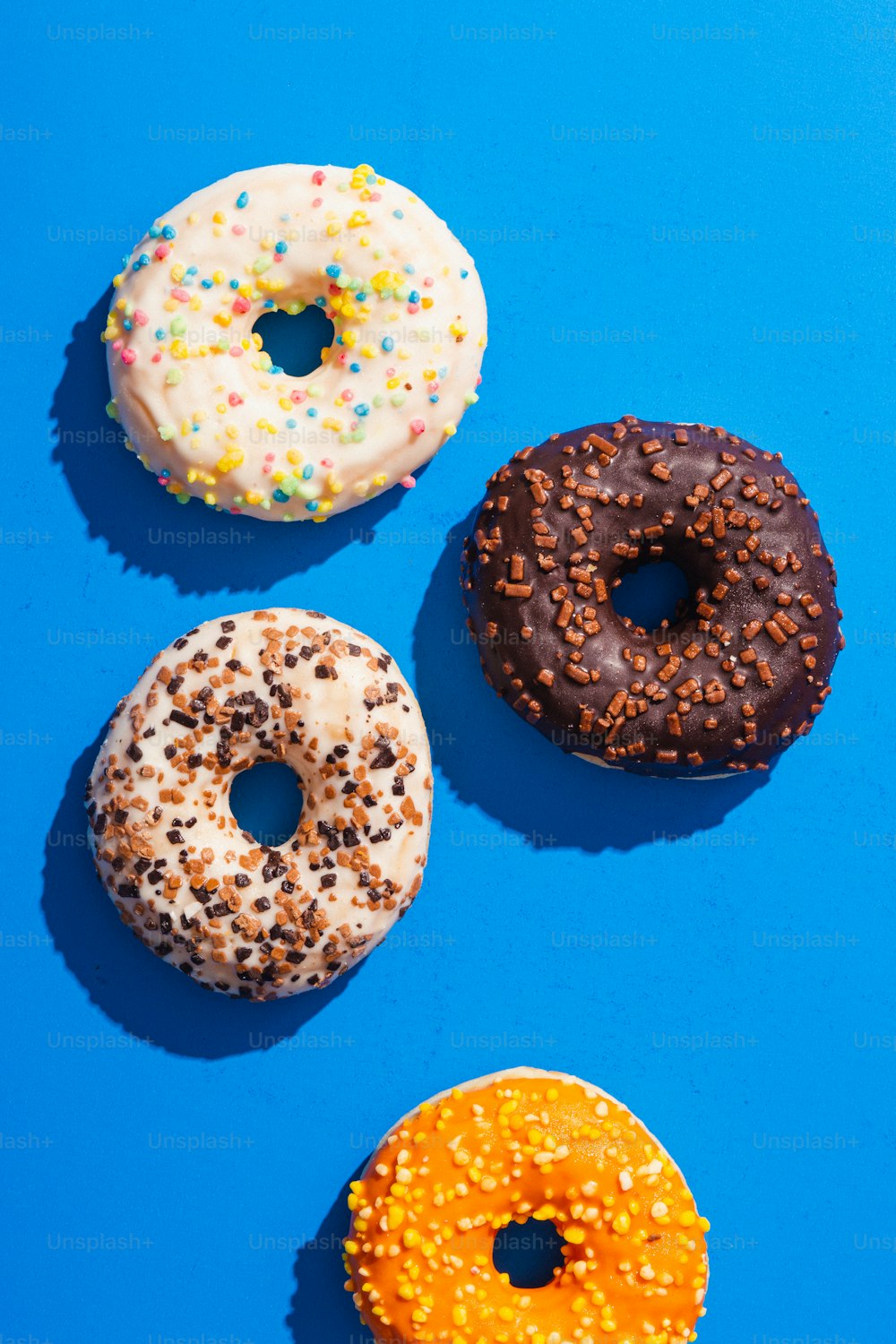 um grupo de três donuts sentados em cima de uma superfície azul