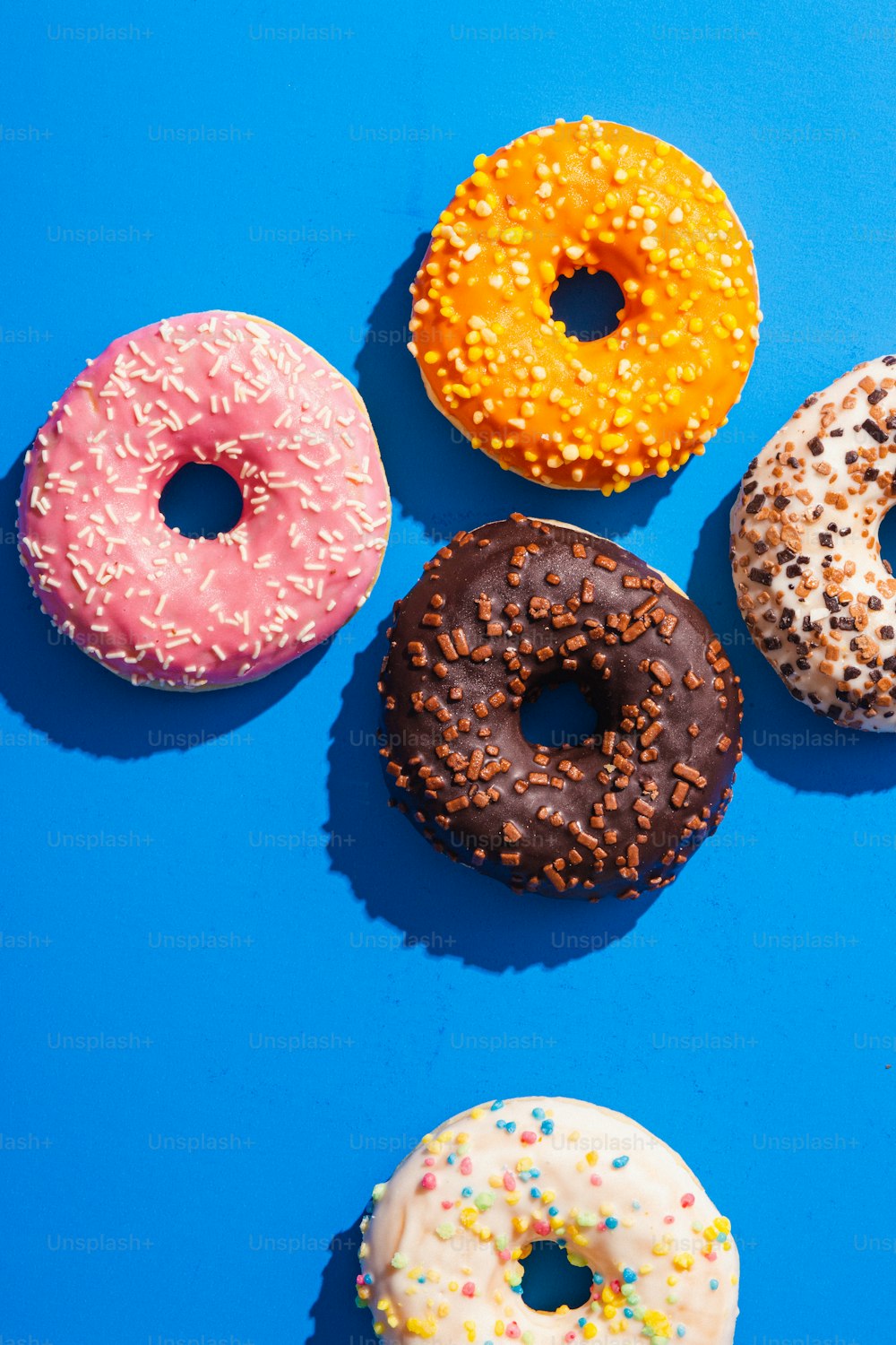 um grupo de quatro donuts sentados em cima de uma superfície azul