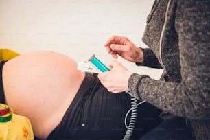 a pregnant woman holding a cell phone while laying on a bed