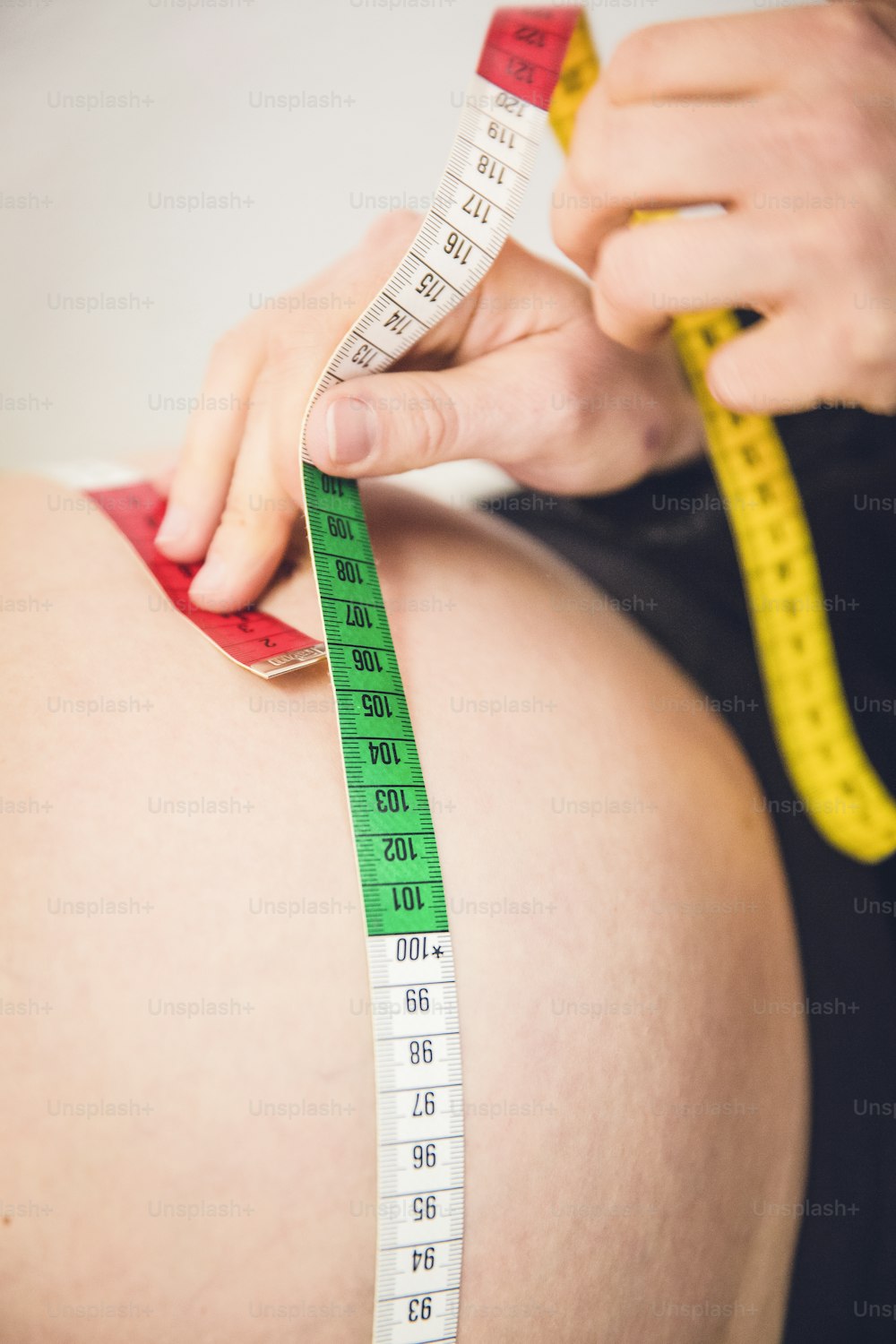 a pregnant woman measuring her belly with a measuring tape