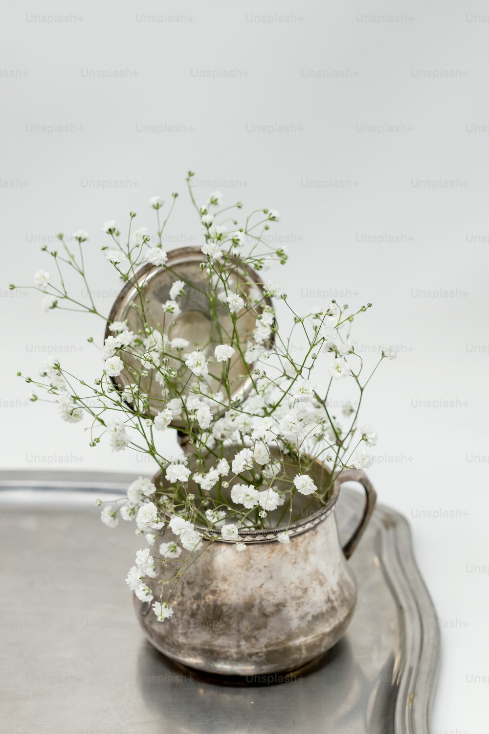 un vase avec des fleurs dedans assis sur un plateau
