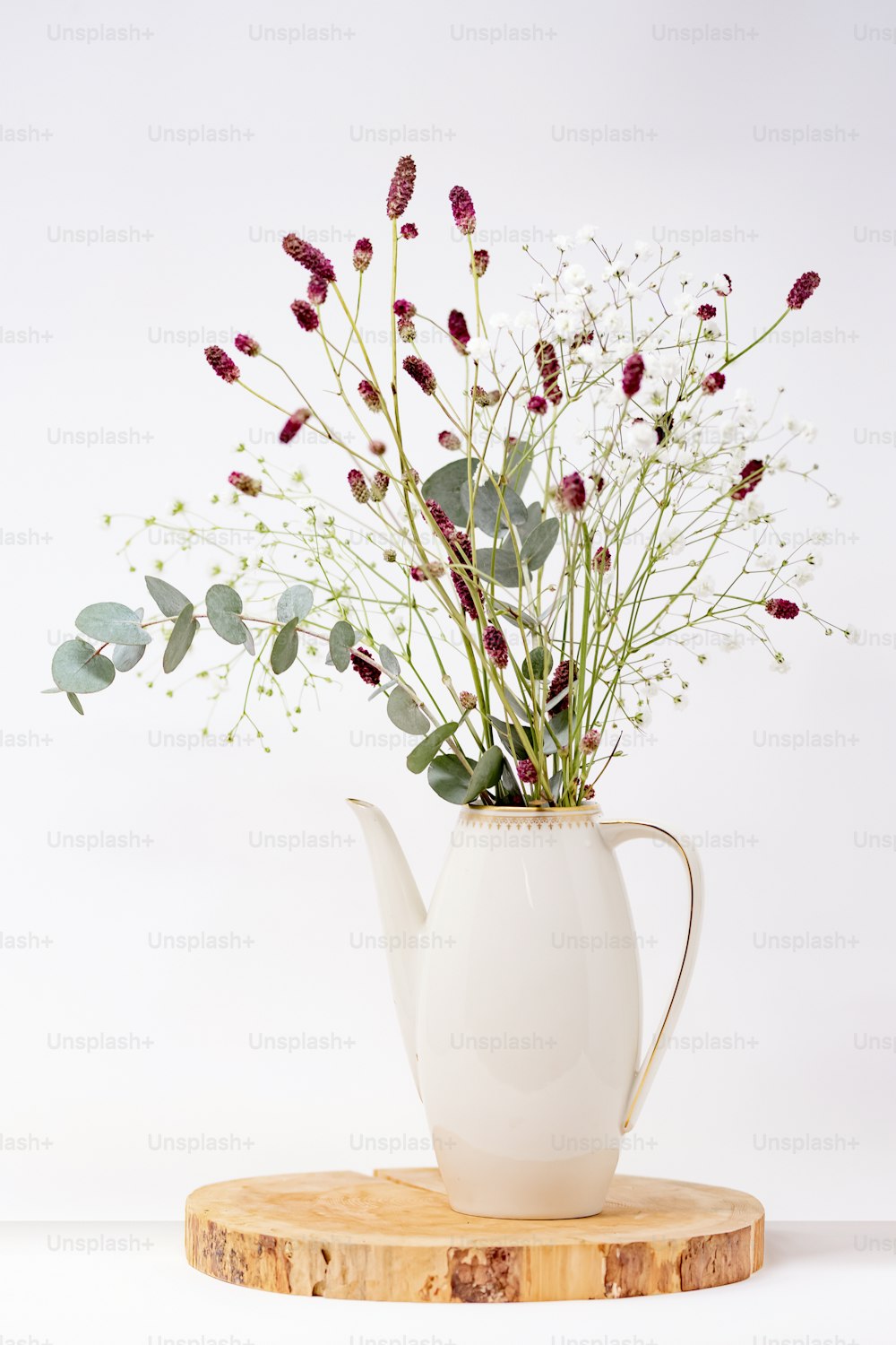 una tetera blanca con un ramo de flores