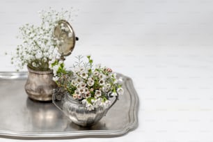 uma bandeja de prata com um vaso de flores sobre ela