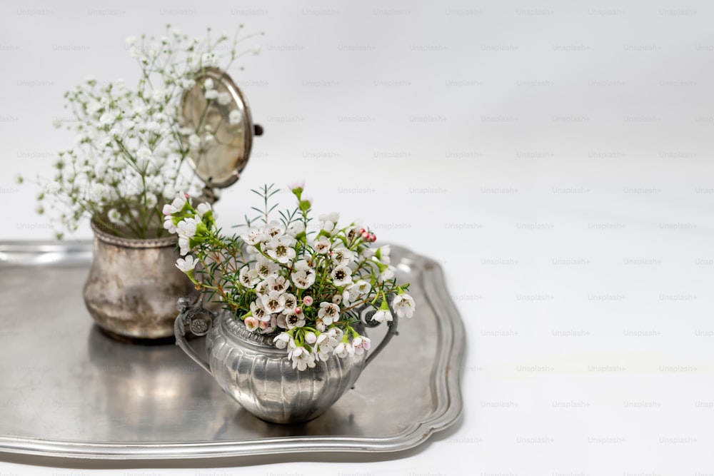 un plateau en argent avec un vase de fleurs dessus
