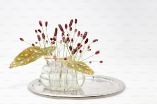 a glass vase filled with flowers on top of a metal tray