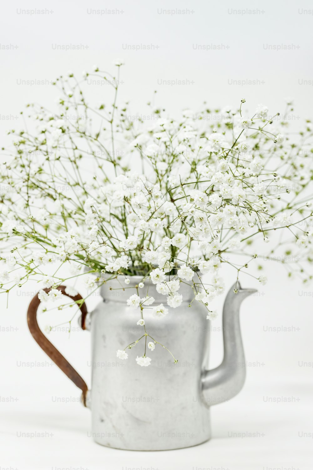 a metal watering can with white flowers in it