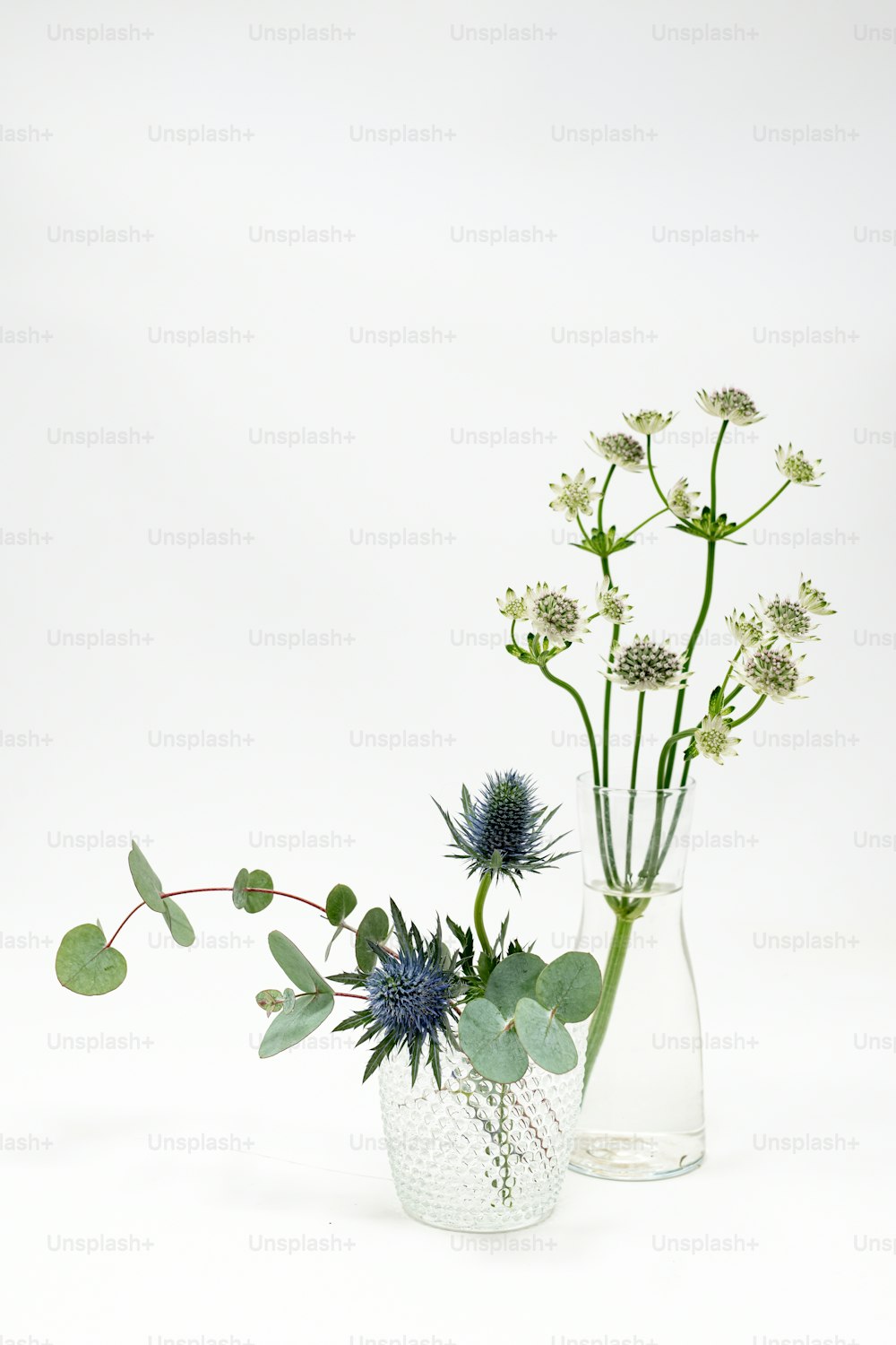 um par de vasos cheios de flores em cima de uma mesa