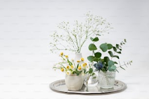 um par de vasos cheios de flores em cima de uma bandeja de metal