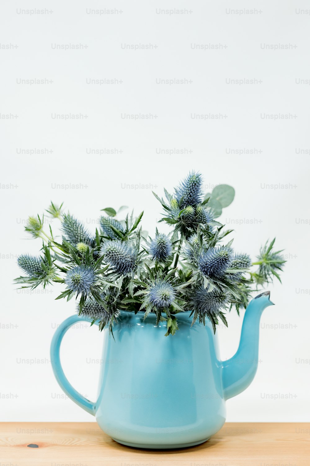 a blue watering can filled with blue flowers