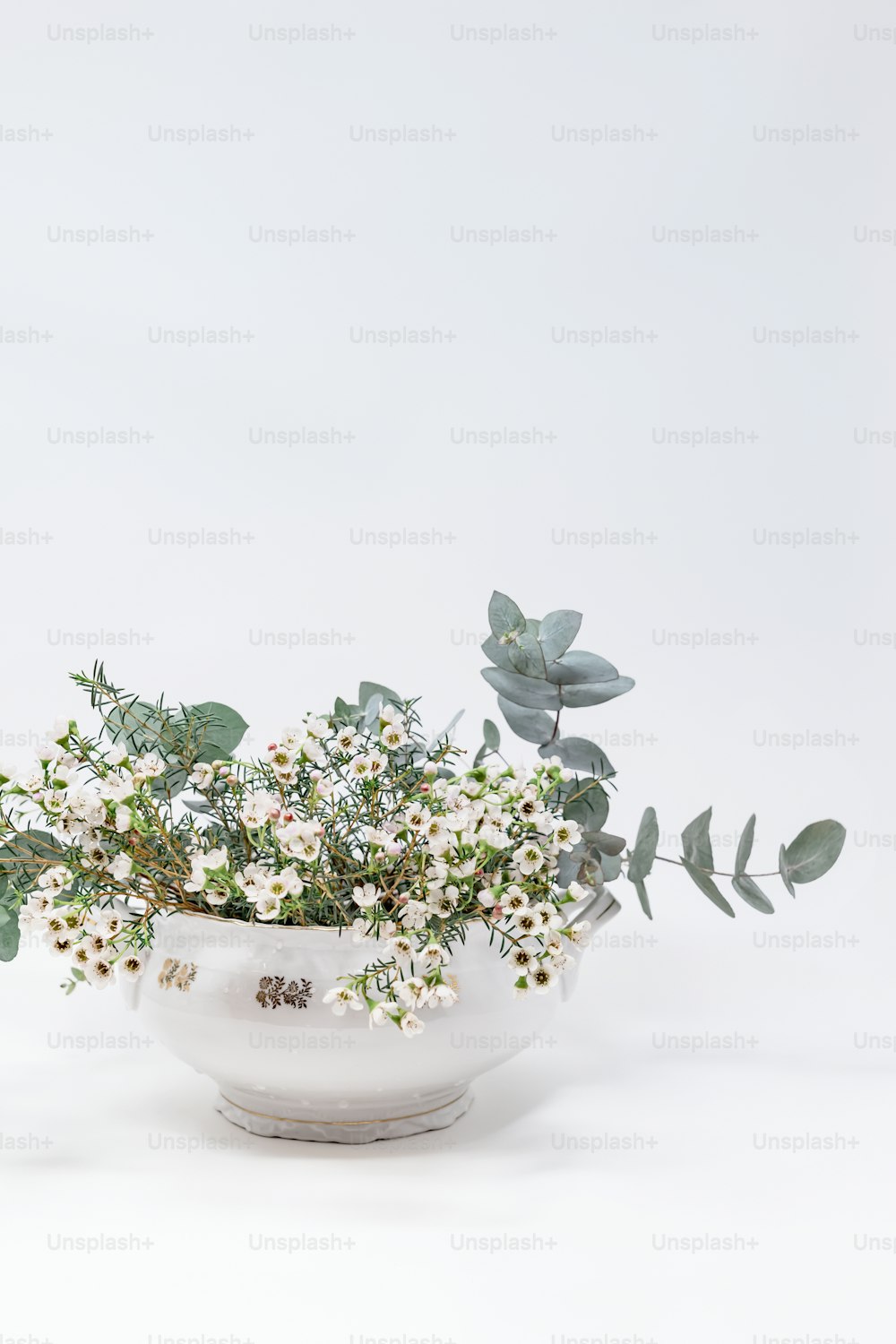 a white bowl filled with flowers and greenery