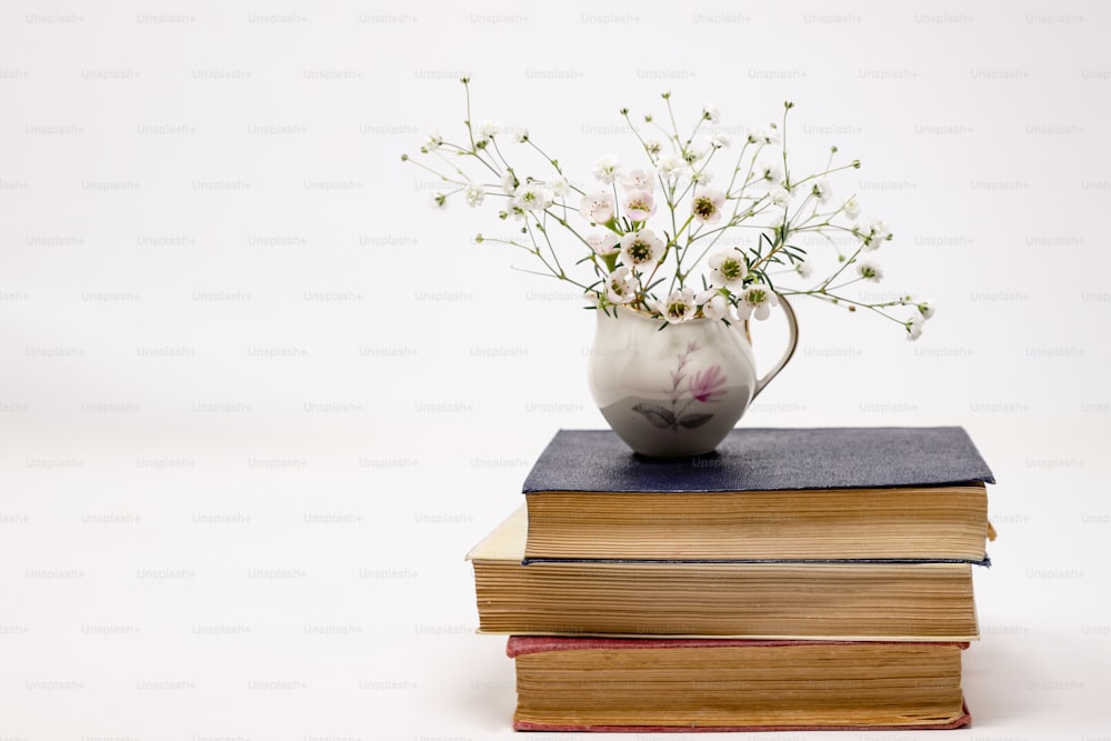 Un jarrón con flores encima de una pila de libros