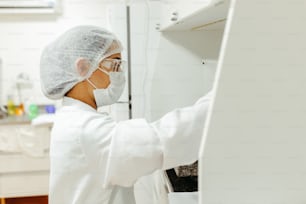 eine Person in weißem Laborkittel und Maske