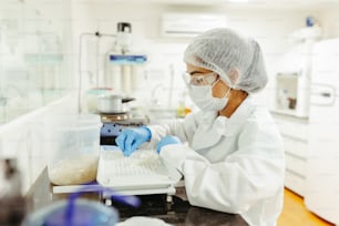 a woman in a white lab coat working on a laptop