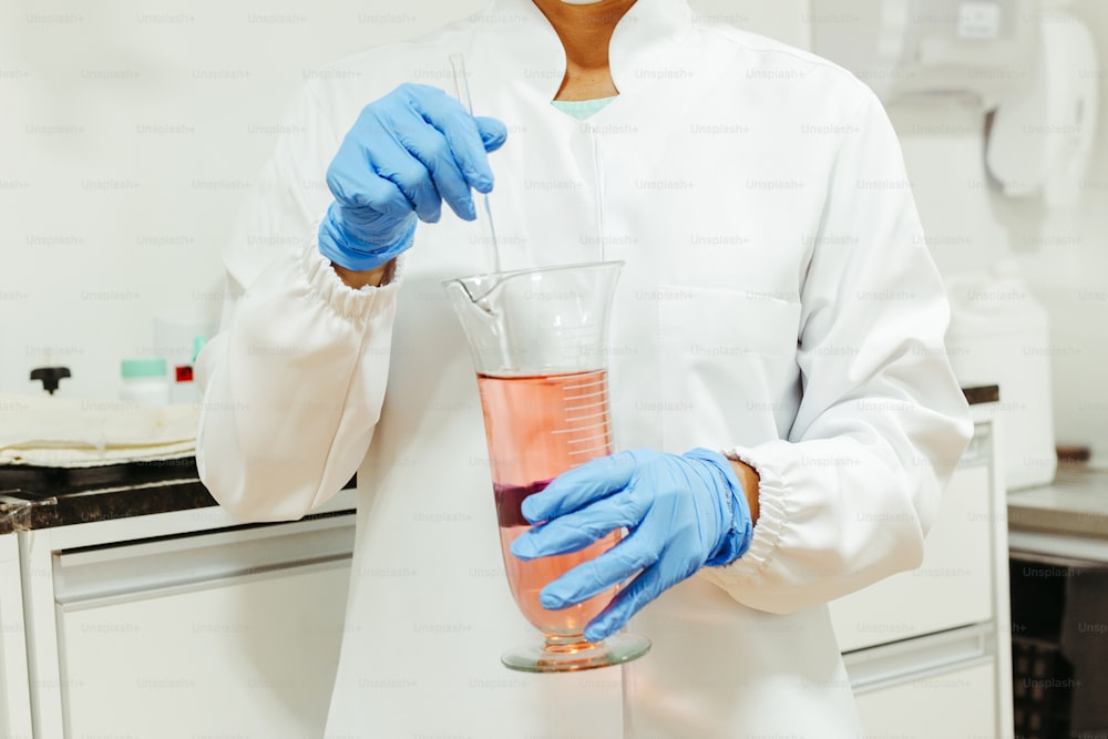 una persona in camice da laboratorio che tiene un becco con un liquido in esso