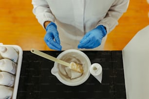 una persona in camice bianco e guanti blu che prepara il cibo